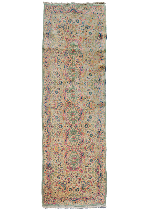 Kerman fragment runner that features a flowing, floral design with scrolls and other baroque elements associated with French Savonnerie rugs.  Bright raspberry pink, light blues, gold and creams on a pistachio ground.
