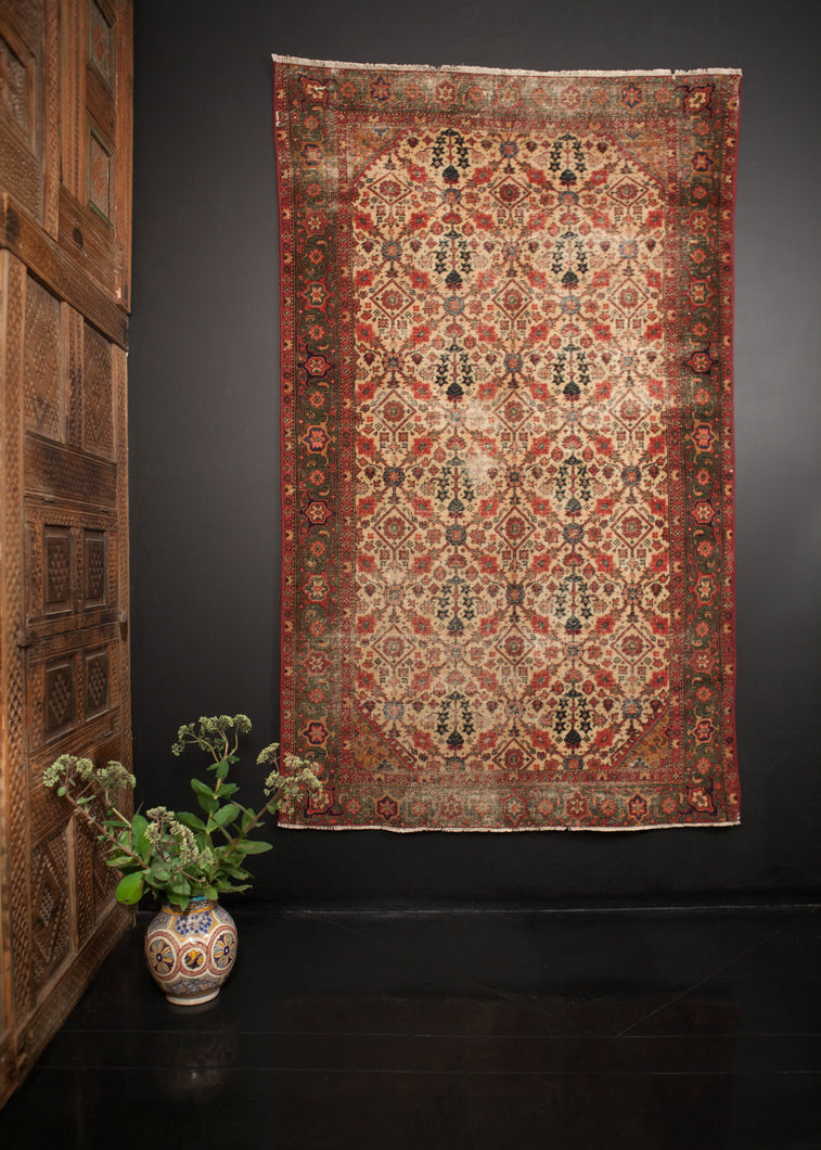 Agra rug handwoven in the early 20th century. Distinct emerald and scarlet border frame an ivory field with shades of blue and pink. 
