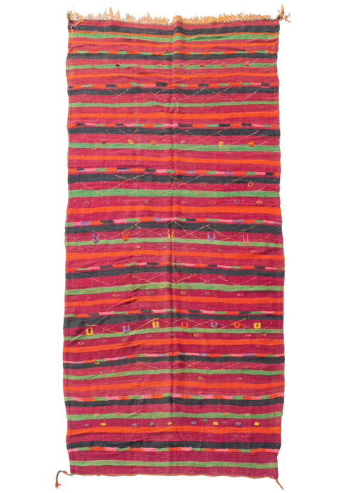 Mid century Moroccan Boujad kilim featuring various stripes with red, orange, bright pinks, highlighter yellow purples and lime green. Colorful diamonds and other protection symbols are embellished over the top.