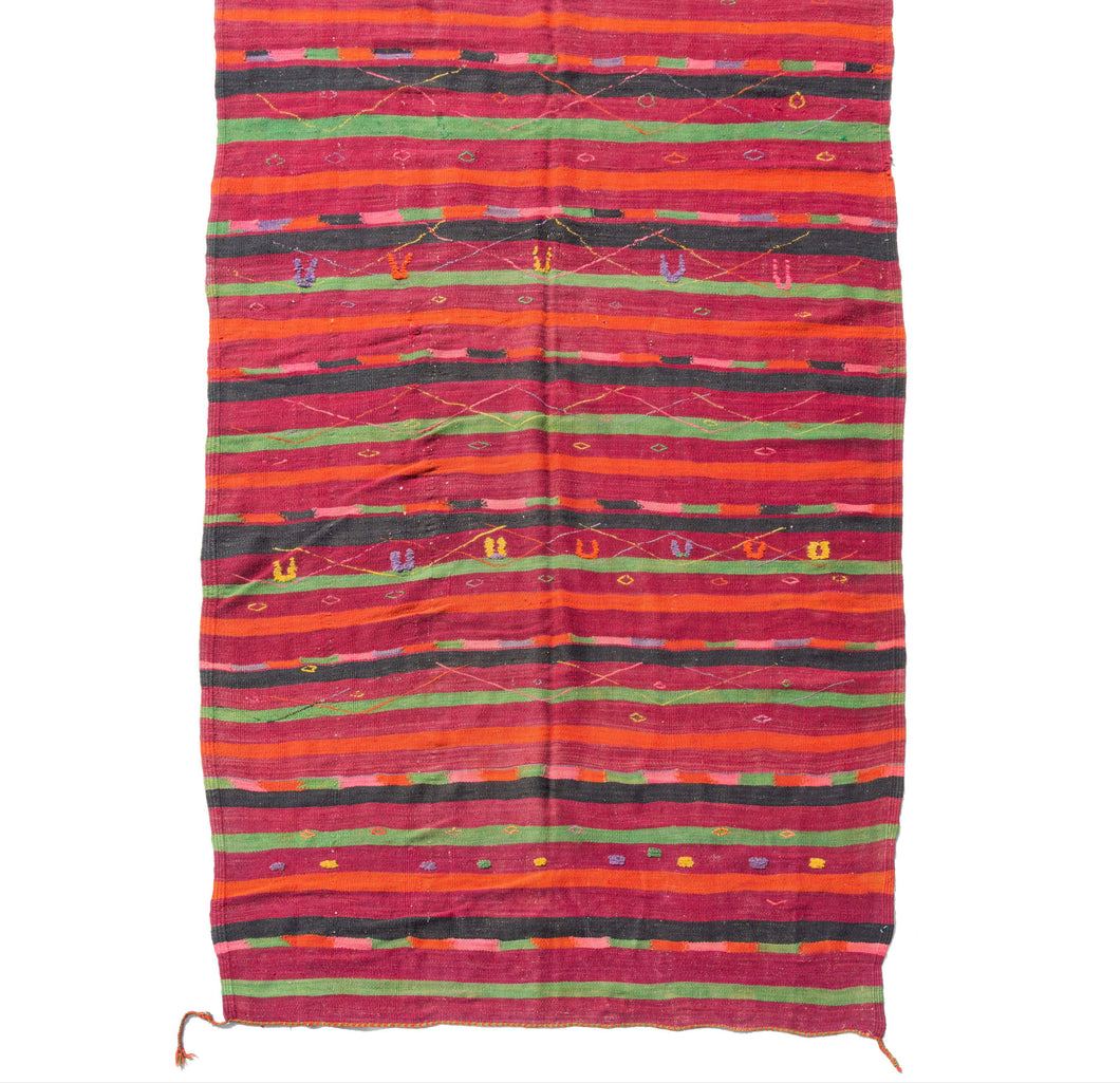 Mid century Moroccan Boujad kilim featuring various stripes with red, orange, bright pinks, highlighter yellow purples and lime green. Colorful diamonds and other protection symbols are embellished over the top.