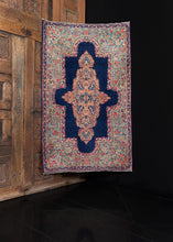 Kerman rug handwoven in central Iran during the second quarter of the 20th century.   A central medallion on a deep blue field, bordered by a complex and small-scale floral design. The color palette is multicolored, with the deep blue anchoring the brighter and pastel colors, which include greens and pinks.    In very good condition, signs of wear consistent with age. Low pile, with a thick, sturdy handle.