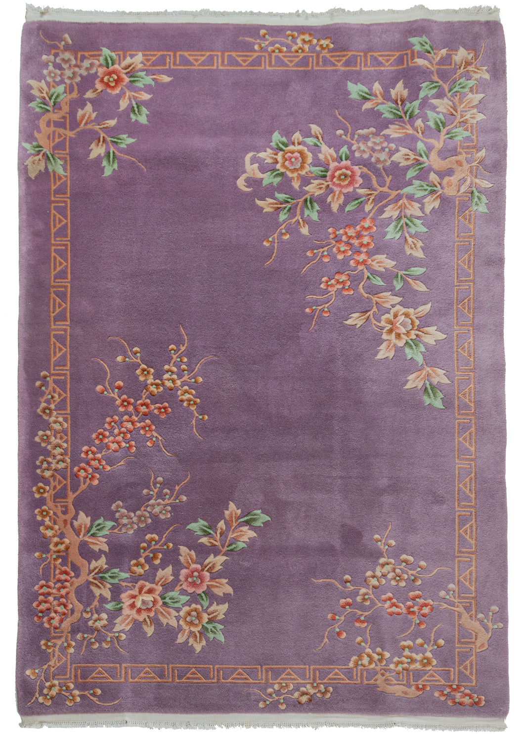 Mid century Chinese deco rug featuring a cheerful purple field. The design is open and borderless, with unique but reciprocating patterning in each corner. Each corner consists of bunches of blossoms in pinks, blues, oranges and greens. The whole is framed by an interlocking 