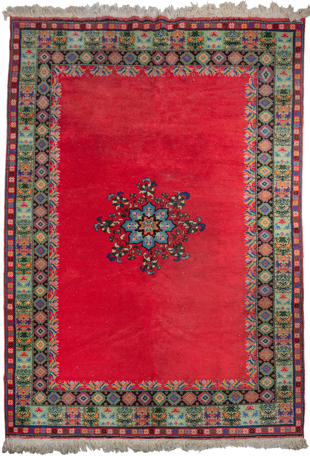Midcentury Moroccan Rabat area rug featuring a bright and expansive candy apple red field unadorned except for a turquoise central medallion and rows of small tulips around the perimeter.  The main border features abstracted flower bouquets in vases on minty green ground and is flanked by two minor borders. Blacks, blues, green, yellow, and hints of orange add zest and diversity to the whole.
