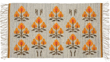 This Vintage Polish Kilim features columns of geometric flowers that alternate between groupings of three and two. The orange flowers have a flame-like quality and really pop against the marled gray ground. It has the original import tag still attached to the back which states the design is called "Roze Goralskie" and the designer as "M. Bujakowa".