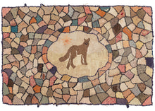 This ANtique Wolf Hooked Rug features a depiction of what appears to be a wolf howling at the sun in its central cartouche. This central is encapsulated by blocks of various colors in an array of shapes pieced together in a lovely mosaic. The fading has made it difficult to differentiate the ground from the sky in the central cartouche. 