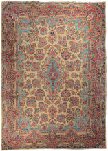 Oversized Persian Kerman carpet featuring an oval central medallion on a soft and shiny ivory field. The central medallion is intricate and curvilinear, with vases containing bouquets on top and bottom. Sprays of flowers, composed of blossoms like roses and carnations, are connected by vines and tendrils. The color palette is composed of light beiges, light and dark blues, pinks and greens. A narrow border with a floral meander completes the design. 