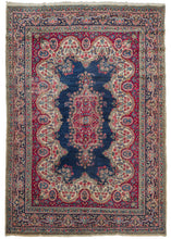 Persian Kerman rug featuring a stunning central medallion with a deep blue field and a curvilinear meandering floral pattern. Bright raspberry pink, light blues, and creams complete the color palette.