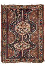 This Antique Khamseh Rug features two connected latch hooked medallions filled with abstracted birds atop a navy of ground chock full of more abstracted birds and rosettes and flanked by two scalloped edges filled with botehs on a rust ground. The whole is nicelhy framed by a bright polychrome border featuring a "ↄc" motif.