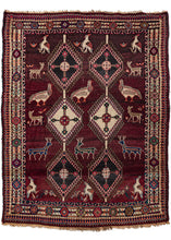 This Vintage Shiraz Rug features two columns of latch-hooked diamonds surrounded by animals on a maroon ground. The animals are large, detailed, and diverse including deer, falcons, and partridges. Framed by an ivory main border in a style more often found in older Qashqai rugs from the region. In good condition with some light color run. Medium pile with a thick, heavy handle.