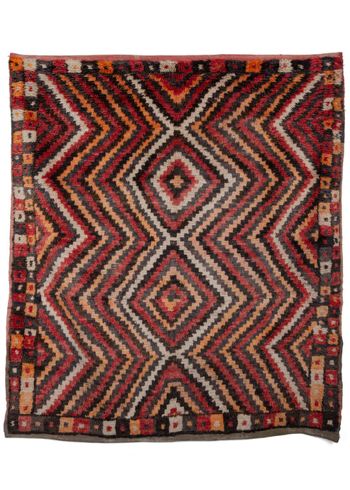 Square Turkish Yatak rug featuring a concentric diamond design that vibrates in a minimalist but effective color palette of reds, oranges, browns, and ivories. The simple double border is composed of little squares in alternating colors. 