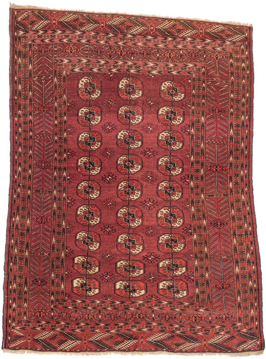 This Tekke main rug was handwoven during the second quarter of the 20th century in Turkmenistan.  The field features a grid of classic plump Tekke main guls and more skeletal latch-hooked secondary guls. Nicely spaced and slightly off-kilter giving it an organic and free-flowing vibe. It is framed by a dynamic main and minor featuring vegetal forms rams head and directional arrows with a simple yet effective palette of deep indigo, ivory, brown, and two reds. In an unusual and very hard to find size for the