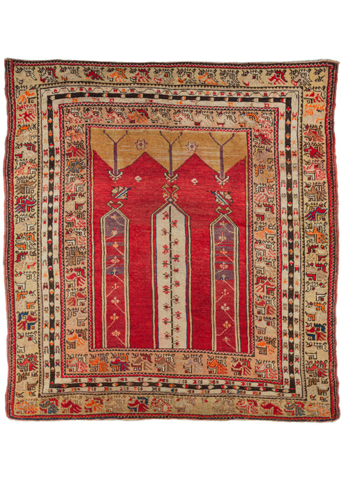 Turkish Karaman prayer rug composed of a bright red field with purple abrash and three columns containing floral motifs climbing towards the top of the rug. The floral motif of the central column could be interpreted as a hyacinth, which was a motif favored by Ottoman courts and later adopted in village rugs. This is chiefly a Turkish motif, and signifies regeneration and fertility. The other two columns contain carnation blossoms, another motif commonly found in Turkish rugs.