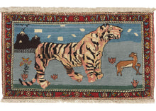 vintage Bahktiari Tiger Pictoral rug featuring a large tiger on a blue field with a small deer to the right. In the background are mountains with clouds and birds in the sky. In the foreground of the scene are flowers and grass.