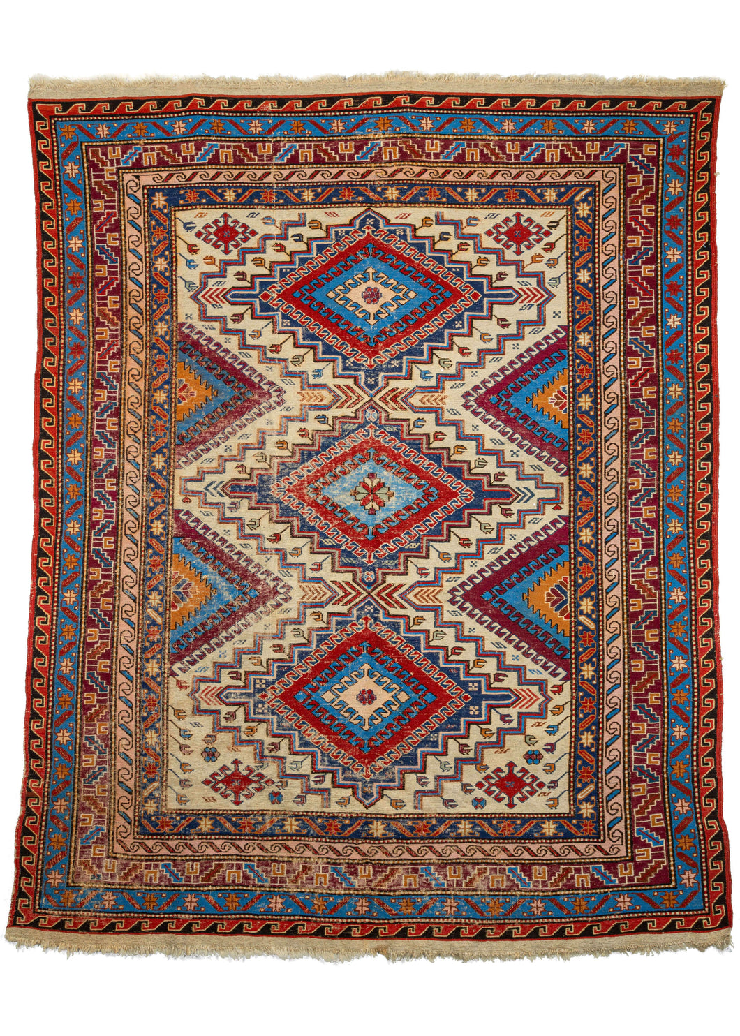 Vintage Caucasian Soumak area rug featuring three latch-hooked concentric diamonds in reds and blues on a bright ivory field. The field is surrounded by multiple distinct borders including greek keys, scrolling 'S's, and most prominently a well-executed calyx and serrated leaf border. 