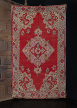 Turkish Oushak rug handwoven during the second quarter of the 20th century.  This rug features a bold central medallion and elaborate cornices, all on a bright red field. The soft mauves and ivories of the design contrast nicely with the brightness of the field, and the black outlines provide detailing to the design. The border is equally ornate as the main field composition.   In good condition, signs of wear consistent with age. Low pile, with a light handle.