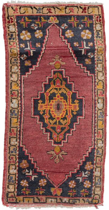 vintage Turkish Yastik rug featuring a warm palette of gold, burgundy, and deep blue, with shots of orange and ivory for contrast. The central medallion is framed by one floral border. Overall easy piece that would work well as a doormat or kitchen sink rug, in excellent condition.