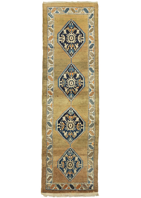 This Camel Serab Runner features a lush camel ground which is vast and open both in the field and around the perimeter. Four lozenges in light and dark blue, ivory, and an electric orange appear to float above the open space. Perfectly framed by a serrated leaf and calyx border in the same tones on an ivory ground. Finished with three rows of selvedge and a thick strip of original kilim end which add strength and structure both visually and in actuality.