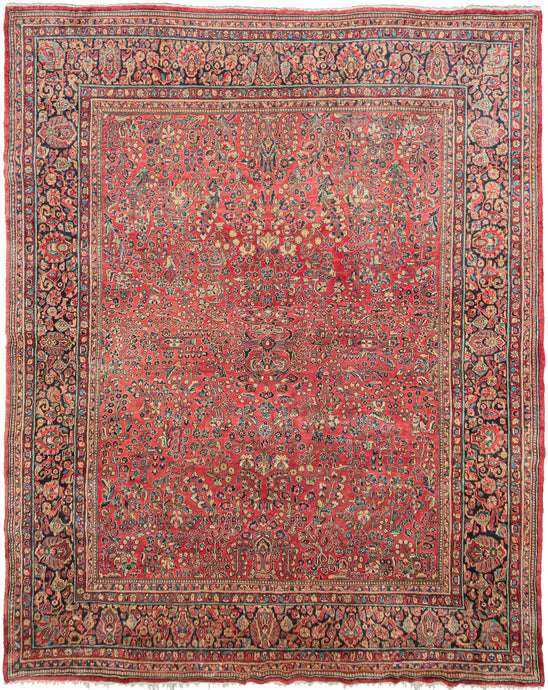 This Sarouk was handwoven in Western Iran during the second quarter of the 20th century.   This rug features a curvilinear floral design on a soft raspberry red field. The floral work is intricate and an excellent example of the type of floral sprays Sarouk rugs are known for. It features a central focal point that blends into the pattern without dominating the composition. The main border features a palmette and blossom design on a navy ground.  