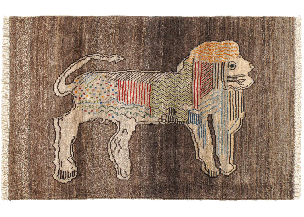 This Patterned Lion Gabbeh features a lion form on an undyed gray wool backdrop. The lion has been stylized with sections of dots, squiggly lines, and another pattern in red, blue, green, and yellow. The pile is densely woven, making this a plush rug.