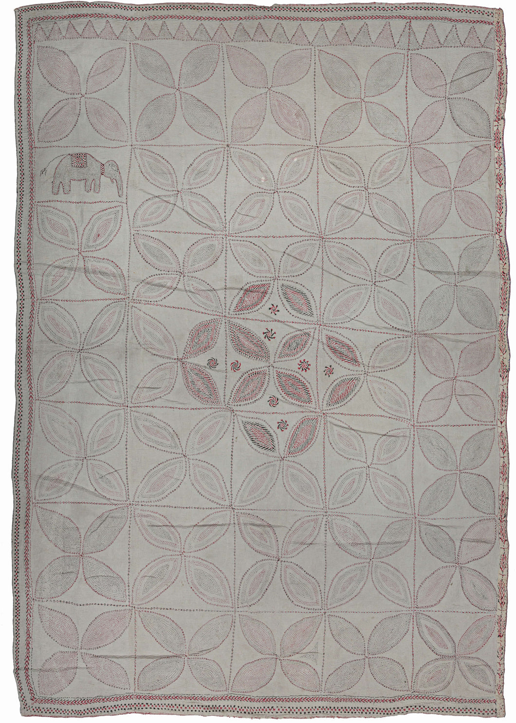 large Antique Bengali Kantha featuring a repeat pattern of quatrefoils in a grid. It has a limited palette of various red and black threads on a plain white cotton ground which is subtle but intriguing. The stitching gets fuller and more saturated in the center and small pinwheel motifs have been added giving the piece a more traditional focal point. The patterning is broken in a section in which the inclusion of an elephant adds some interest.