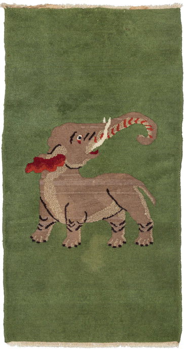 Small deco runner featuring a wonderful composition of a small elephant looking back with its trunk lifted upwards, atop an open grass green ground. Well executed in two tones of gray with details of rich red in the trunk and ears and striking ivory eyes and tusk. In classic feng shui, an elephant with raised trunk represents good luck, wealth, and success.